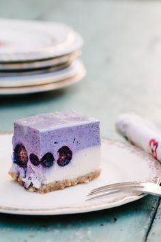 a piece of blueberry cheesecake on a white plate with silverware next to it