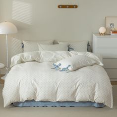 a bed with white sheets and blue bows on the comforter is in a bedroom