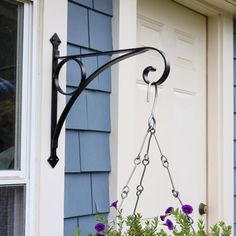 a planter with purple flowers hanging from it's side next to a blue house