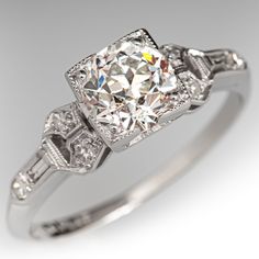 This lovely architectural circa 1920s Art Deco ring is centered with one (1) old European cut diamond, weighing 0.95 carats, that is prong set in a square frame with milgrain edging. Each shoulder is accented with three (3) bead set round single cut diamonds, and one (1) bezel set baguette cut diamond. The shoulders also have milgrain edges. The ring measures 6.2mm at the top, rises 6.1mm above the finger, tapering to 1.3mm wide and 1.0mm thick at the base of the shank.  The ring is crafted in platinum and is currently a size 5.  One of the baguette diamonds has a tiny corner chip that cannot be seen while worn. Luxury Single Diamond Art Deco Ring, Luxury Art Deco Diamond Ring With Prong Setting, Luxury Diamond White Sapphire Art Deco Ring, Luxury Art Deco Ring With Polished Finish, Luxury Diamond White Art Deco Diamond Ring, Luxury Art Deco Ring With Brilliant Cut, Luxury Art Deco Rings With Brilliant Cut, Platinum Art Deco Diamond Necklace, Luxury Art Deco White Sapphire Ring