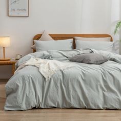 an unmade bed in a bedroom with white walls