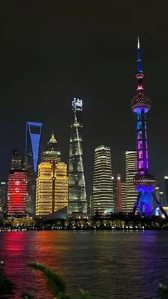 the city skyline is lit up at night with brightly colored lights and skyscrapers in the background