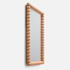 a mirror that is on the wall with some wood beads hanging from it's sides