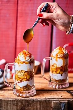 a person spooning some food out of a glass mug on top of a wooden table