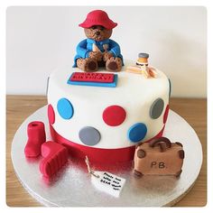 a cake with a teddy bear sitting on top of it and other items around it