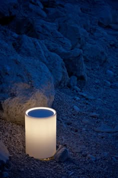 a white light sitting on top of a rock covered ground