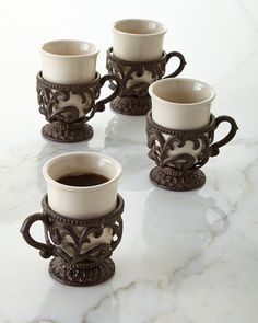 four coffee mugs sitting on top of a marble counter