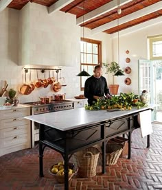 a man standing in a kitchen next to a table with fruit on top of it