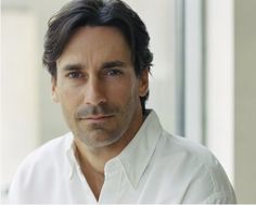 a close up of a person wearing a white shirt and looking at the camera with a serious look on his face