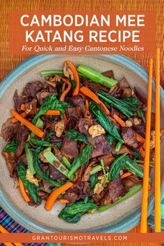 a plate with carrots, meat and broccoli on it next to chopsticks