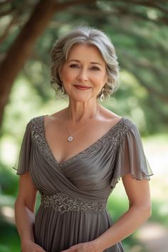 an older woman in a gray dress posing for a photo with her hands on her hips