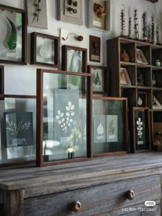 many framed pictures are hanging on the wall above a wooden dresser with drawers and drawers