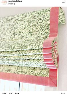 an instagramted photo of roman blinds with pink and green patterns on them, hanging from a wall