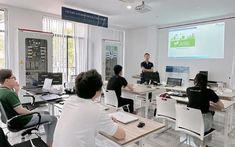 a group of people sitting at desks in front of a projector screen on the wall