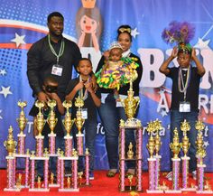 the kids are posing with their trophies at the awards ceremony in front of an american flag backdrop