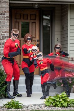 a group of people in costumes standing on the front steps of a house with their arms around each other