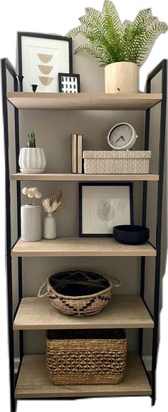 a book shelf with baskets and pictures on it, next to a potted plant