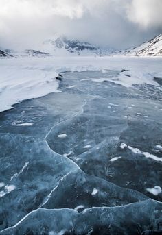 an ice covered river with snow and mountains in the backgrounnd, taken from above