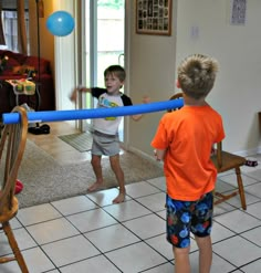 two young boys playing with a blue ball in the living room