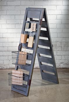 a ladder shelf with baskets on it next to a stuffed animal and other items in front of a brick wall