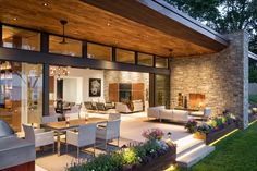 an outdoor living room and dining area at night with lights shining on the outside wall