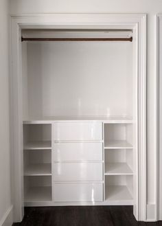 an empty white closet with shelves and drawers in the corner, next to a wooden floor