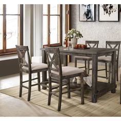 a dining room table with four chairs and a vase on the floor next to it