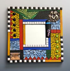 a colorful mirror with an artistic design on the front and sides, hanging on a wall