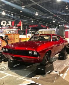 a red muscle car on display in a showroom