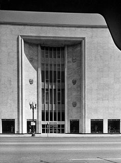 an old black and white photo of the front of a large building with tall windows