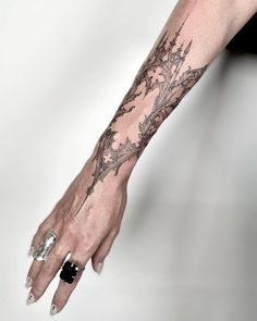 a woman's arm with tattoos on it and a flower tattoo on the wrist