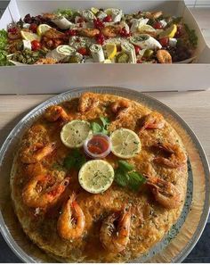 two plates with different types of food on them, one has shrimp and the other has lemon wedges