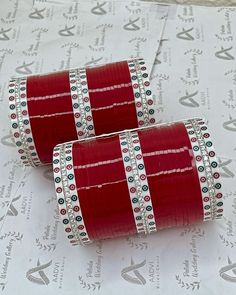 two rolls of red tape sitting on top of a piece of paper covered in white and black beads