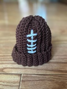 a crocheted beanie with a skeleton on the side sitting on a wooden floor