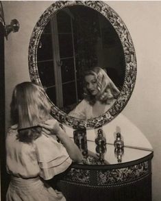 a woman is brushing her hair in front of a mirror and looking at herself in the mirror