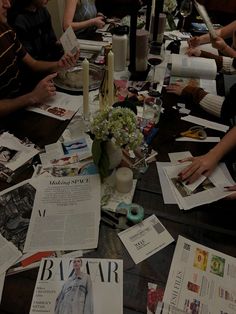 a group of people sitting around a table with papers and candles on top of it