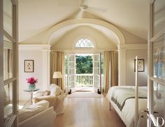 a bedroom with a large bed sitting next to a living room filled with white furniture