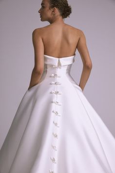 a woman in a white wedding dress with flowers on the back