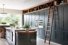 a kitchen with an island and ladder in the center, surrounded by blue cabinetry