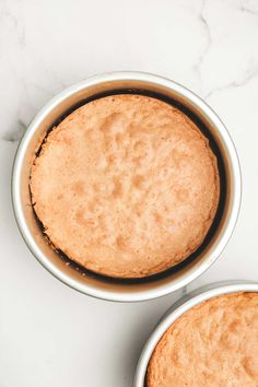 two white bowls filled with cake batter sitting on top of a marble countertop next to each other