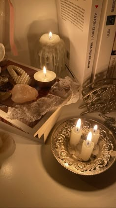 two candles are lit in front of an open book on a table with other items