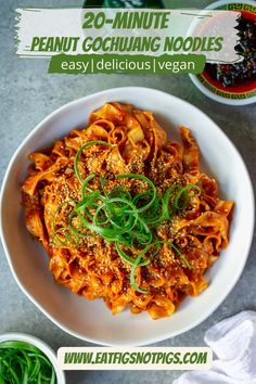 a white bowl filled with pasta covered in sauce and garnished with green onions