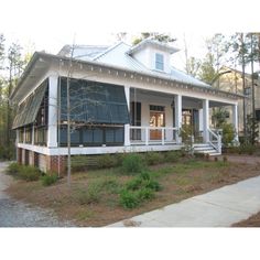 a small white house with blue shutters on the front and second story, surrounded by trees