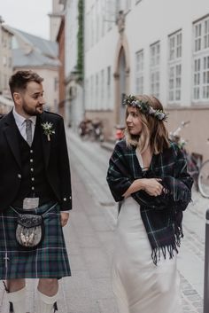 a man in a kilt standing next to a woman