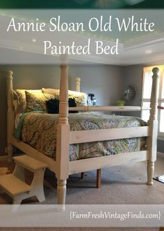 a white bed sitting under a green ceiling in a bedroom next to a wooden step stool