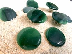 several green stones sitting on top of sand