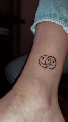 a person with a tattoo on their ankle that has two circles in the shape of faces