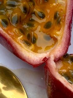 two halves of a pomegranate on a white surface with a spoon next to it