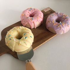 three doughnuts on a wooden board with a spatula