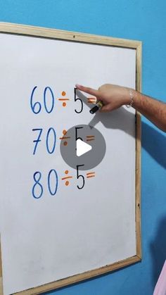 a man is pointing to a white board with numbers on it